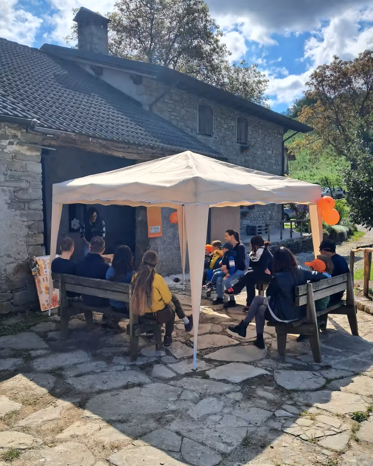 Bambini seduti al banco durante una giornata in apiario, all’ombra di una tenda