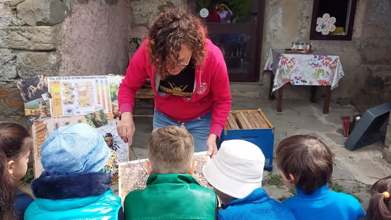 Un’adulta mostra a un gruppo di bambini un’arnia aperta