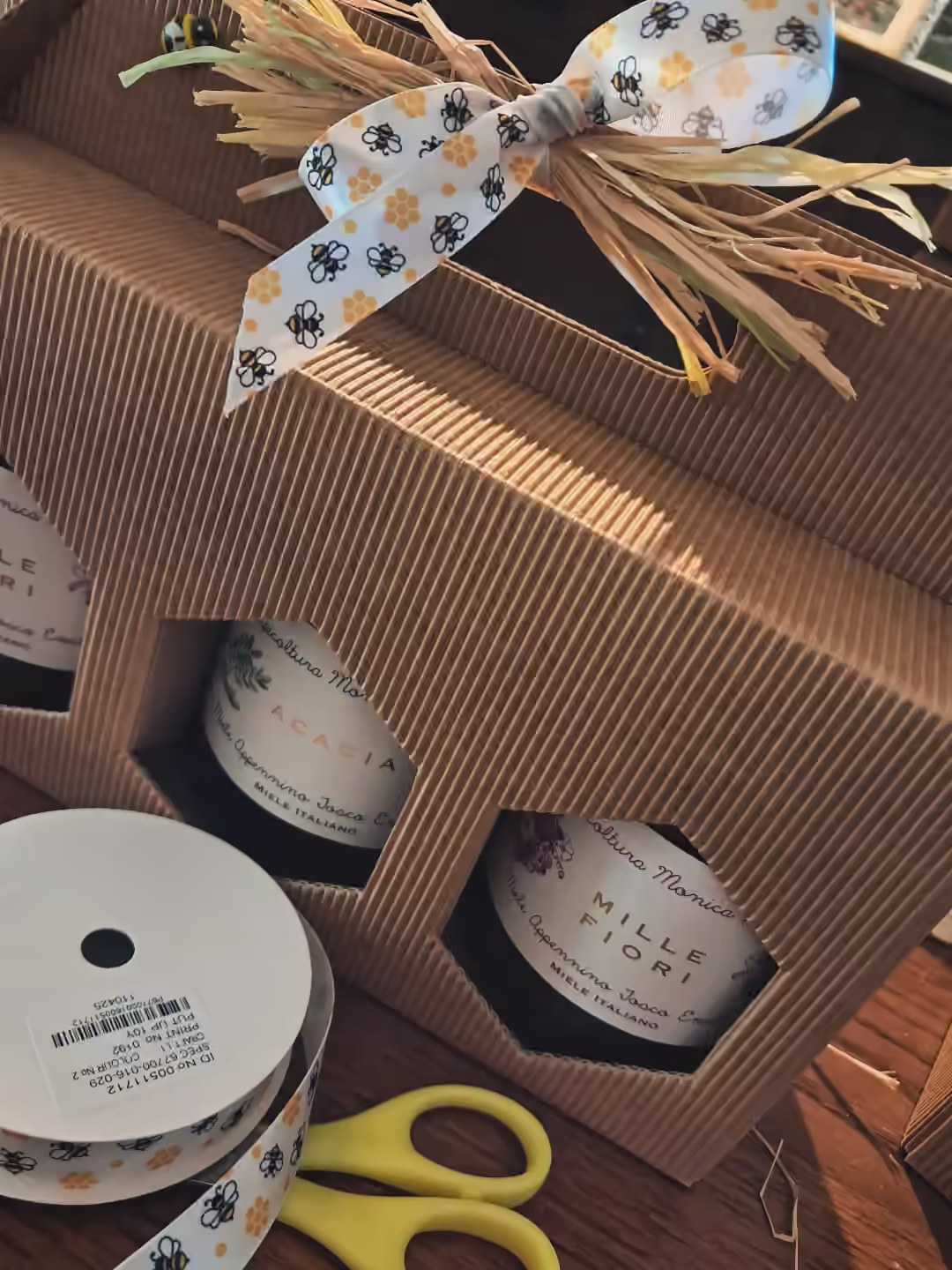 Confezione regalo con vasetti di miele e un nastro decorato con api